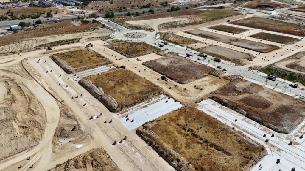 Vista aérea de las obras de urbanización de Los Ahijones, con parcelas, calles e infraestructuras en construcción.